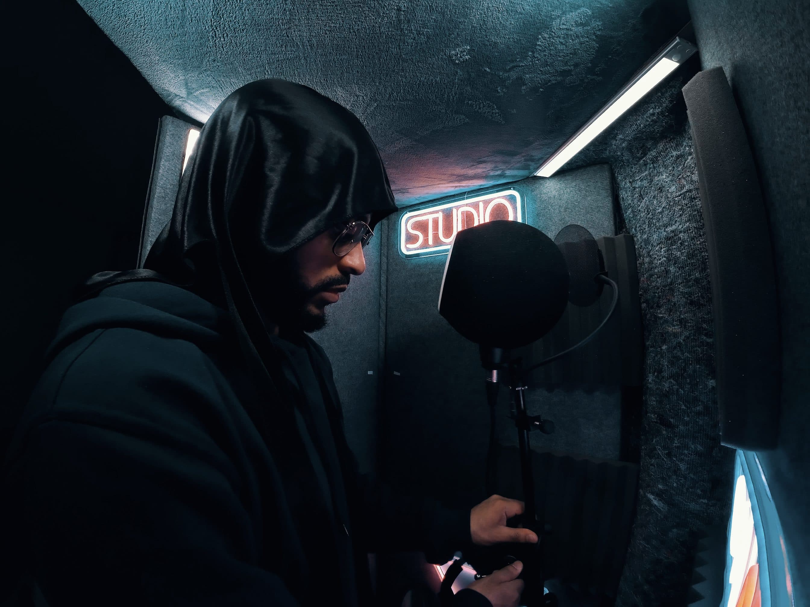 WINZ in the vocal booth, hood up, neon light